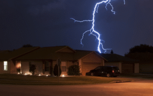 Single‑family home illuminated at night with a lightning strike in the background, symbolizing severe weather and disaster‑response readiness.