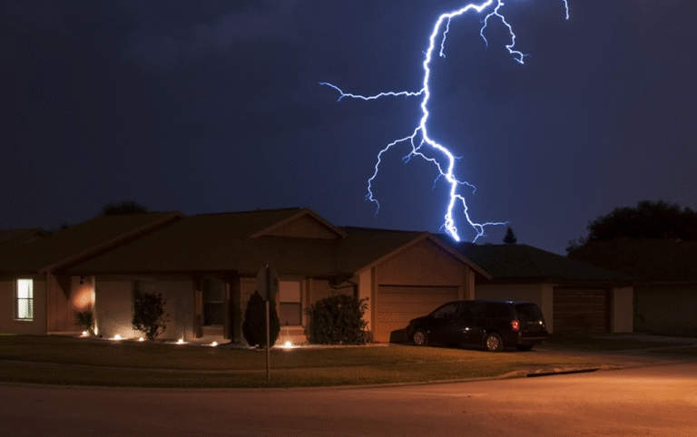 Single‑family home illuminated at night with a lightning strike in the background, symbolizing severe weather and disaster‑response readiness.