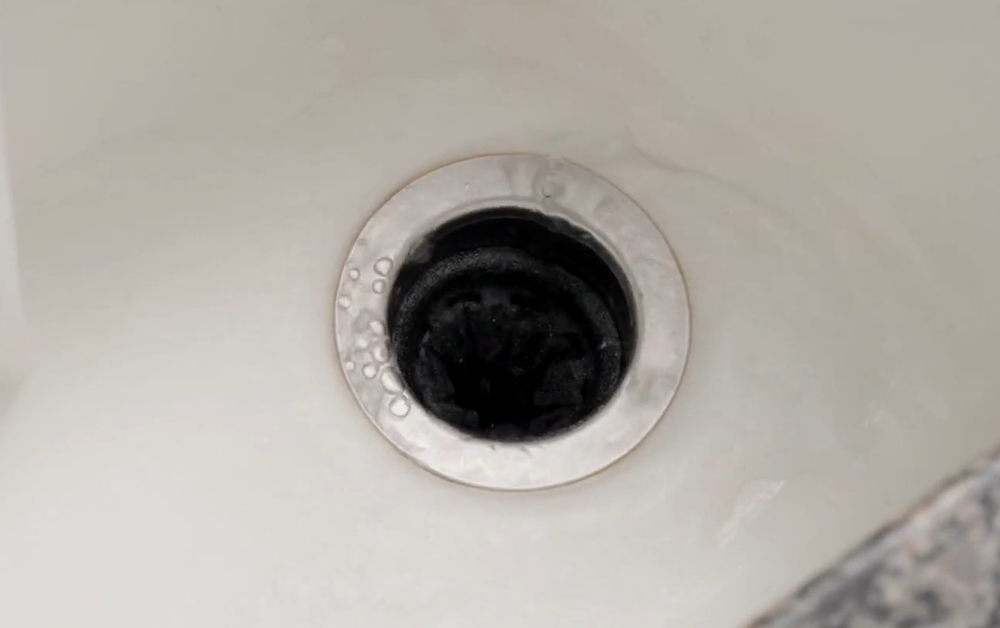 Sink drain with a garbage disposal opening seen from above.