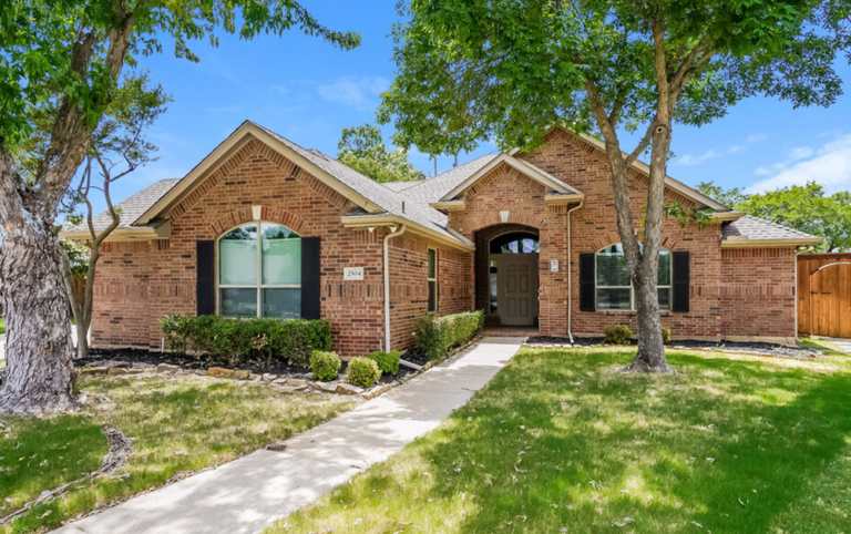 Brick single-family home with a landscaped front yard and shaded walkway, representing safe and affordable housing opportunities for families through Housing Choice Voucher programs.
