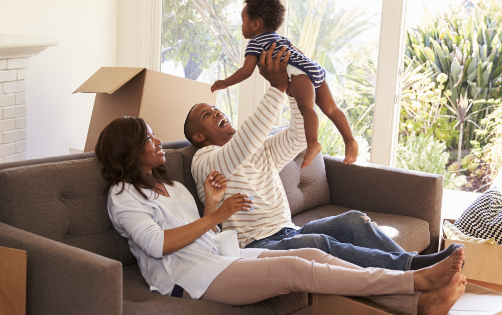Family relaxing together in a living room surrounded by moving boxes after moving into a new home.