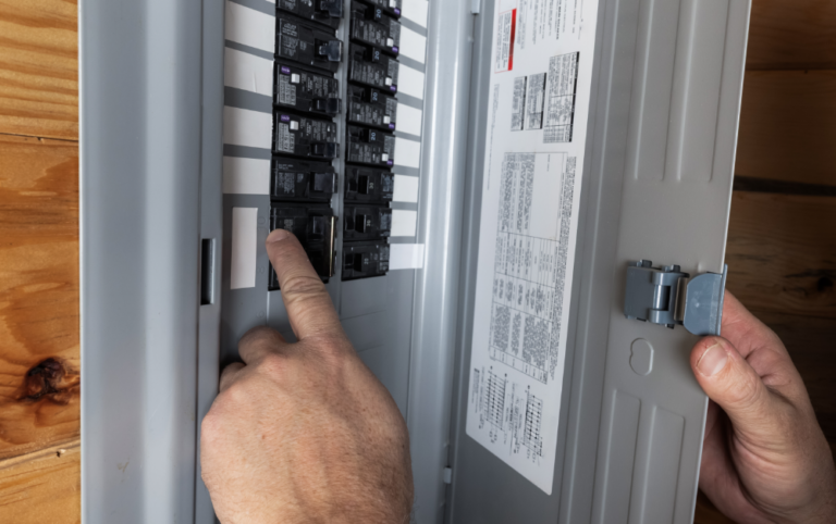 Person inspecting a home's electrical breaker panel to identify a tripped circuit breaker during a power outage.